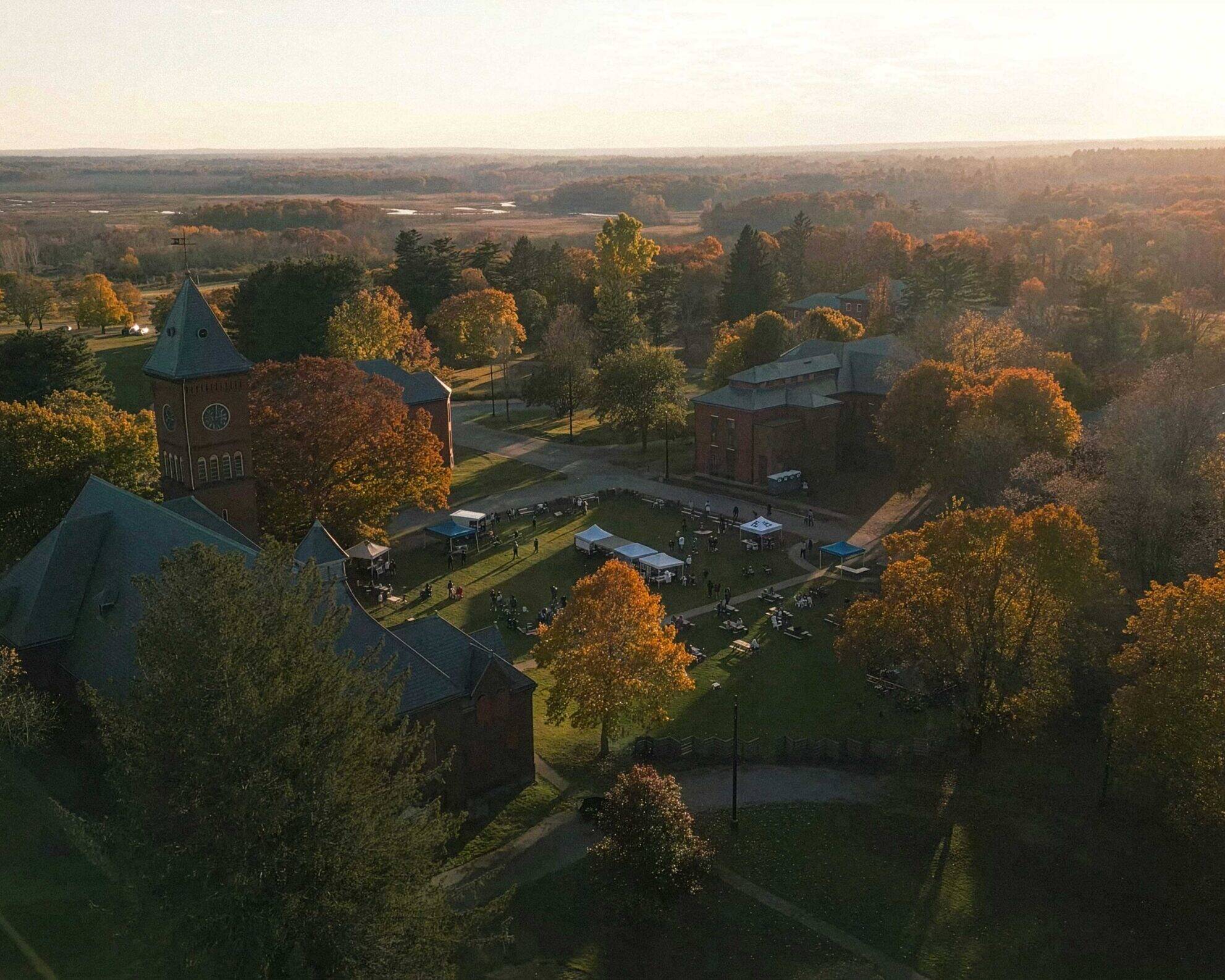 Aerial view of the Bellforge Arts Center campus at sunset, showing the Lee Chapel and Infirmary among autumn trees
