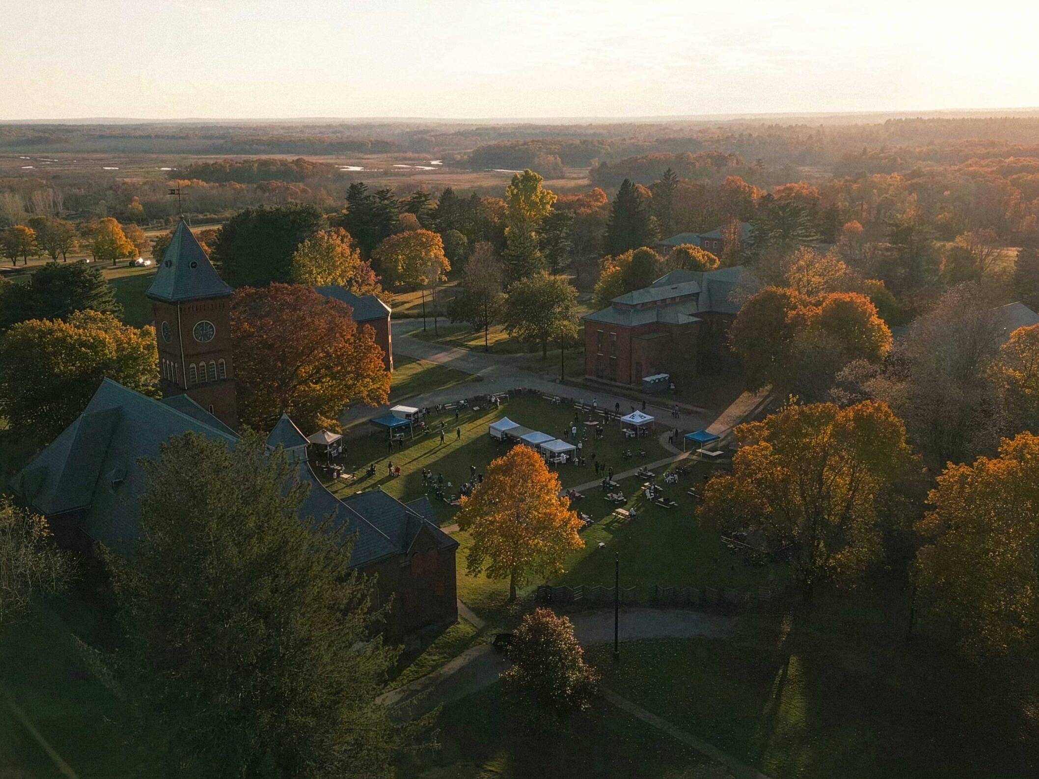 Aerial view of the Bellforge Arts Center campus at sunset, showing the Lee Chapel and Infirmary among autumn trees