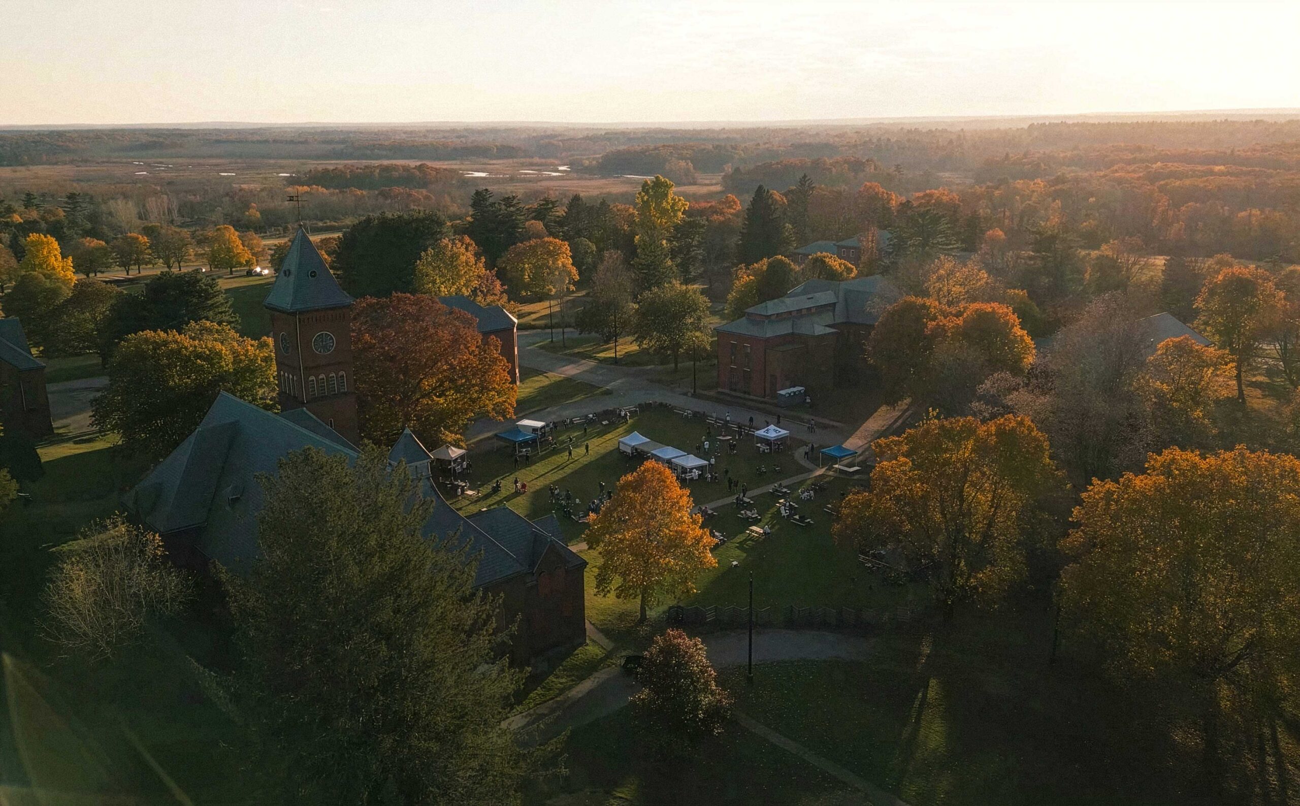 Aerial view of the Bellforge Arts Center campus at sunset, showing the Lee Chapel and Infirmary among autumn trees